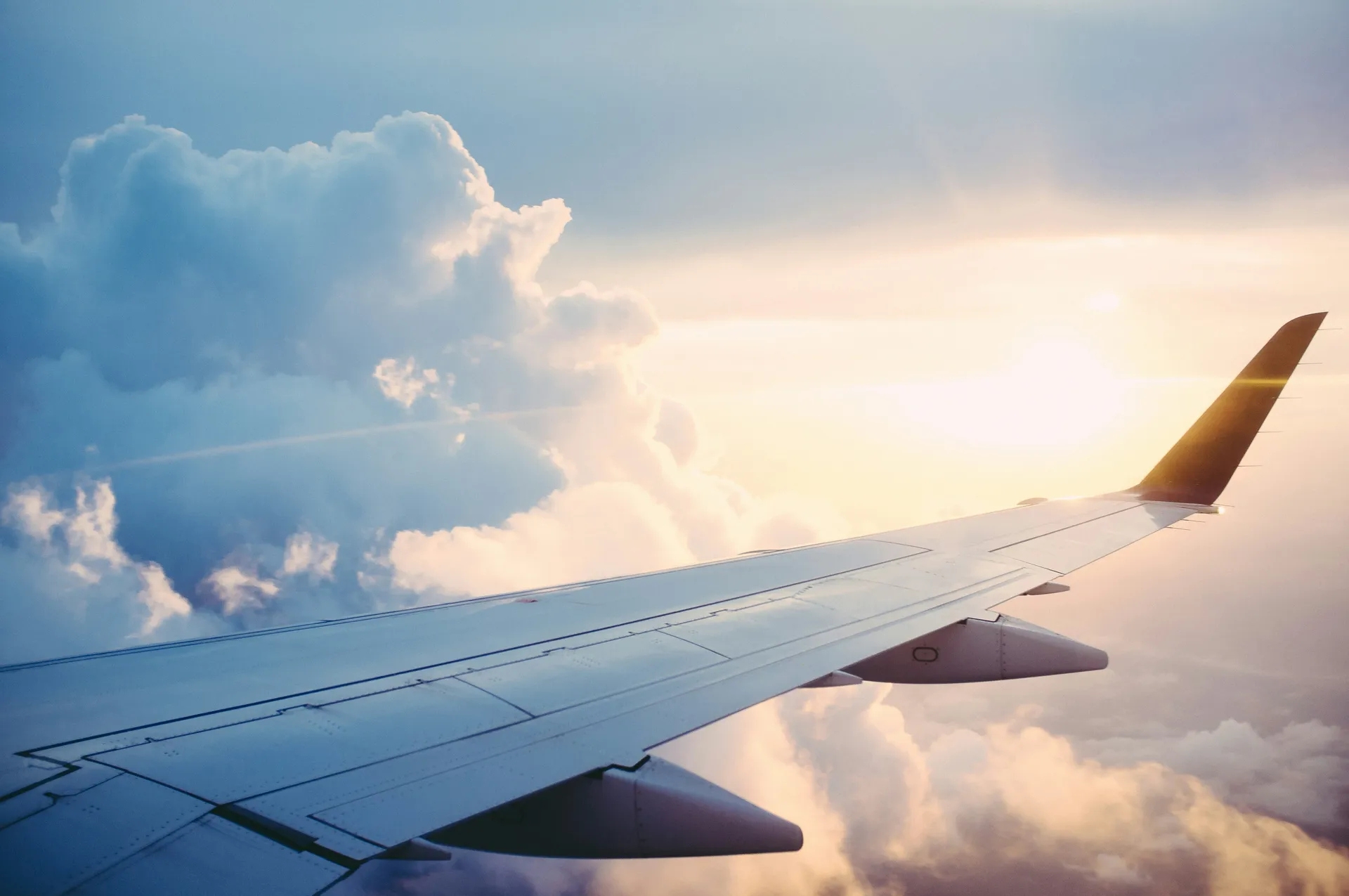 Commercial aircraft wing above the clouds at sunset