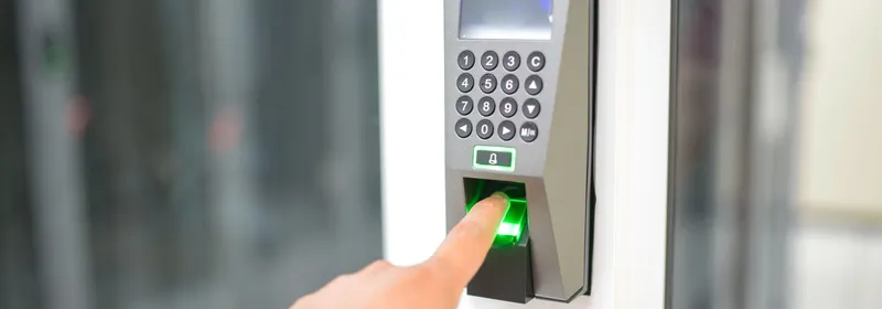 Person placing a finger on a biometric fingerprint reader next to a door